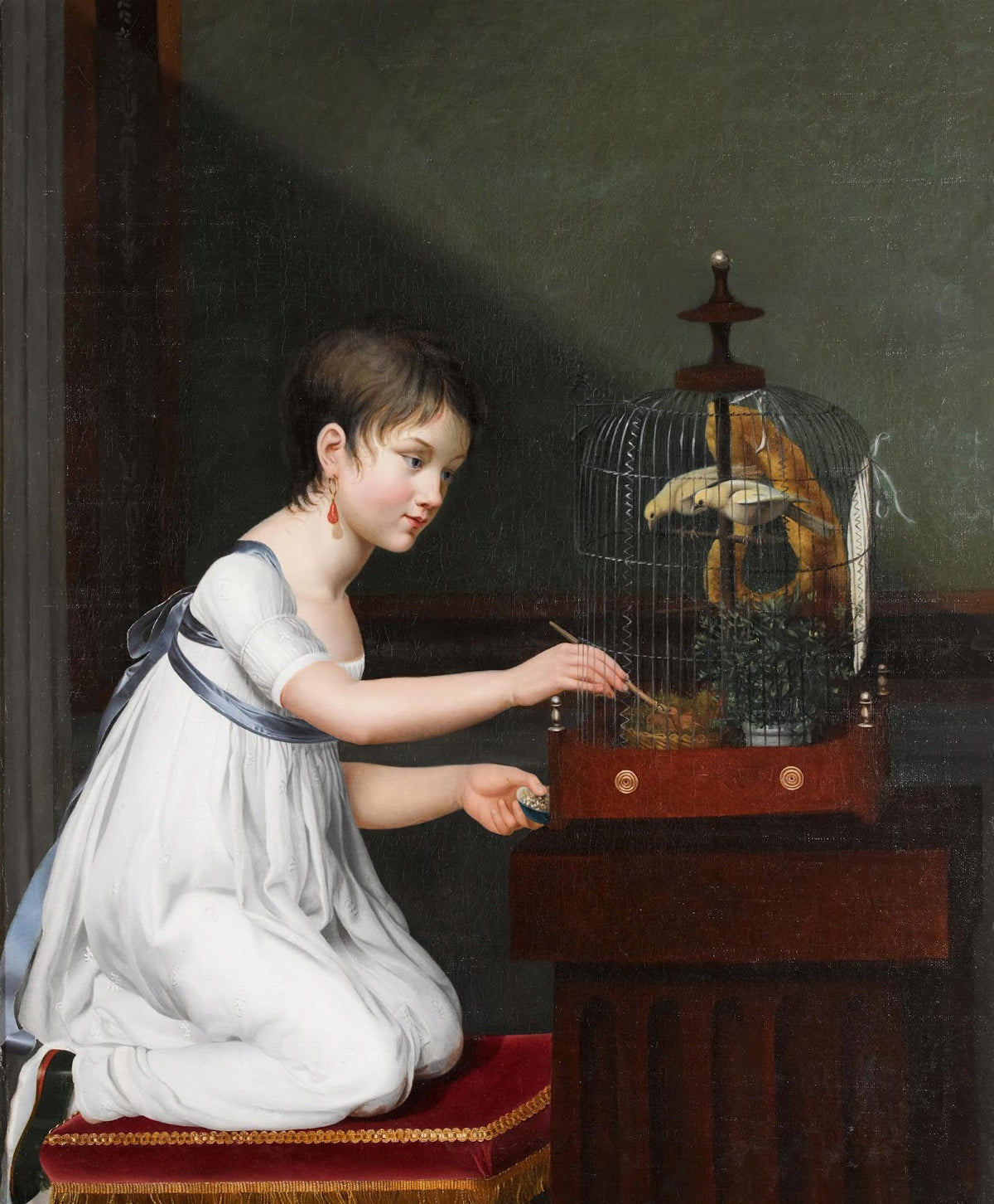 A Young Girl In A White Dress With A Green Sash Kneeling By A Bird Cage While Te